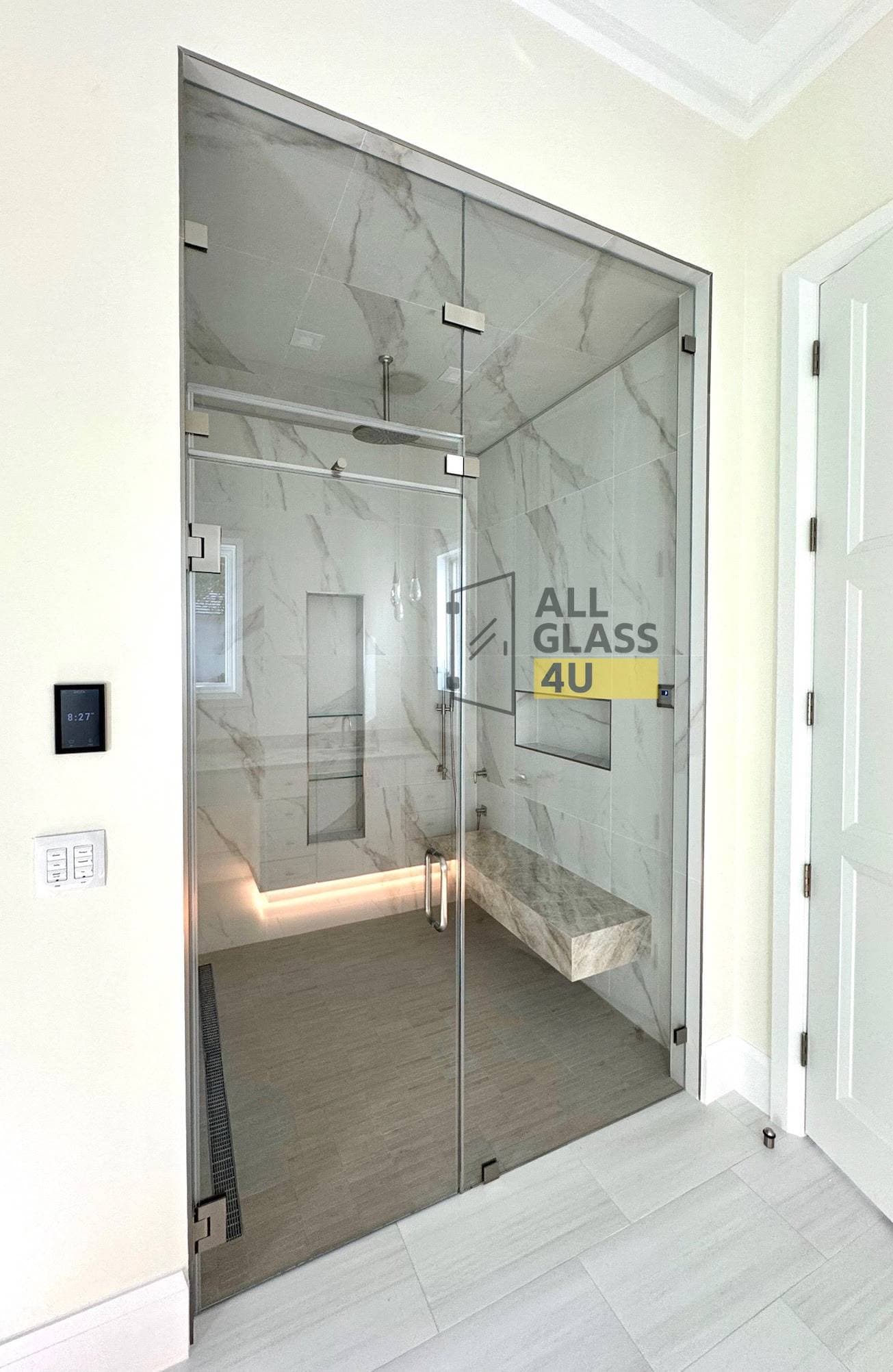 Frameless steam shower enclosure with a bench seat and glass running to the ceiling