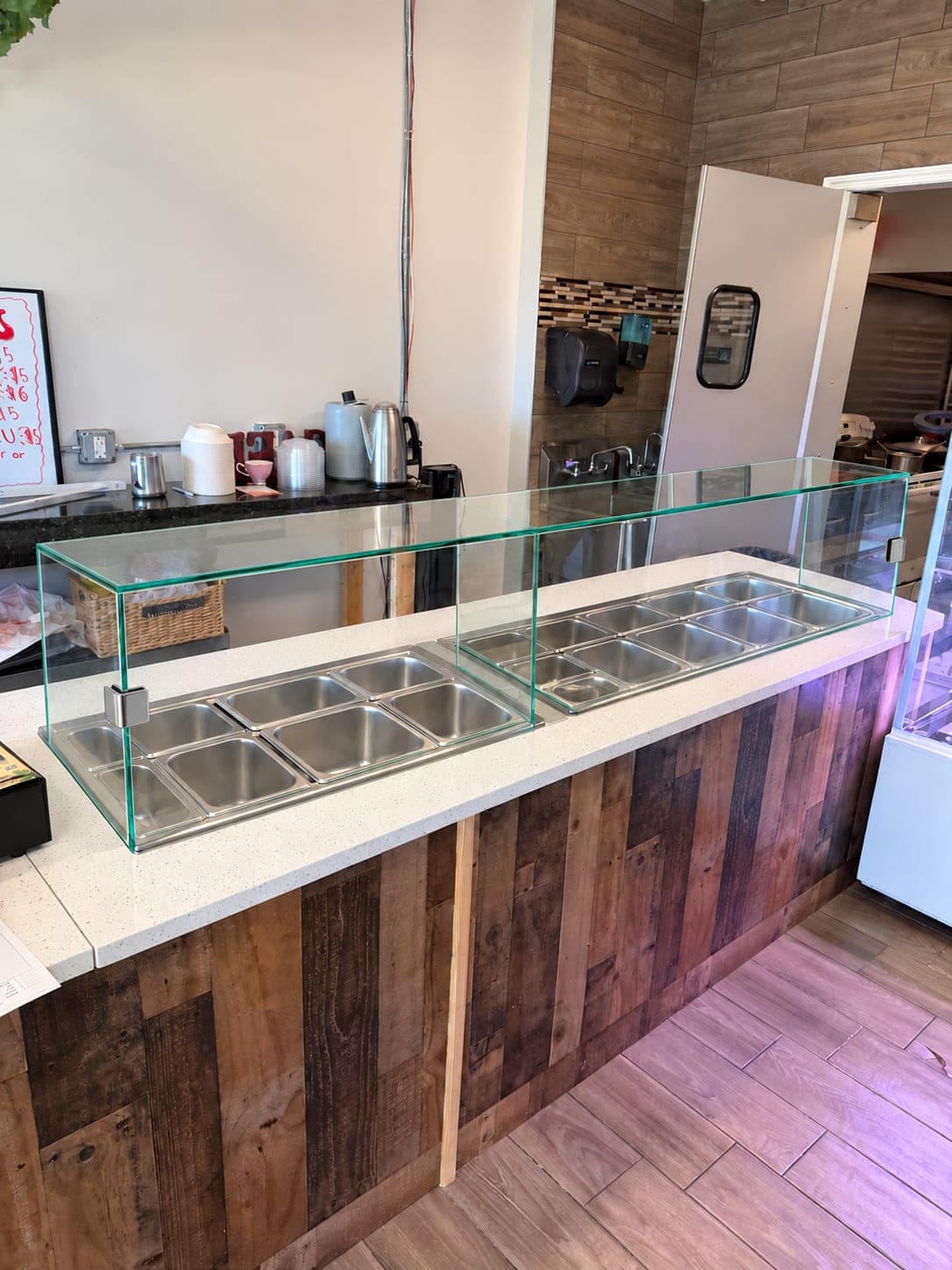 Frameless glass sneeze guards over a restaurant's hot and cold food wells, installed by All Glass 4 U